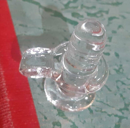 Sphatik Shivling, 4-inch crystal pooja showpiece placed on a textured surface with a red border, highlighting its design.