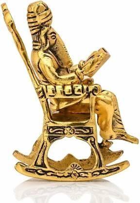 Side view of the Golden Lord Ganesha statue on a rocking chair reading Ramayan, emphasizing the artistic metalwork and elegant posture.